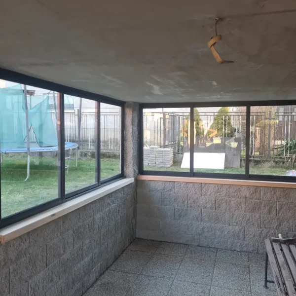 Zboku pohľad na zasklený priestor pod terasou, z interiéru, vo Vysokej nad Kysucou, antracitové zasklenie.