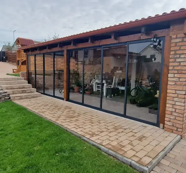 Predný pohľad na zasklený tehlový altánok v Holíči s posuvným zasklením v antracitovej farbe.