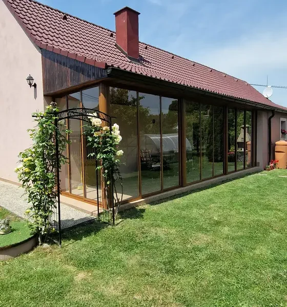 Celkový pohľad na zasklenú terasu v hnedej farbe z diaľky.
