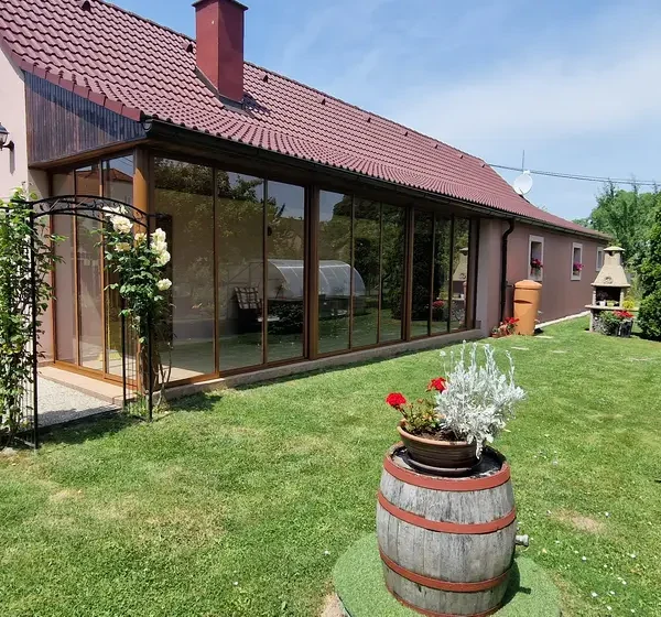 Pohľad z exteriéru na zasklenú terasu v hnedej farbe.