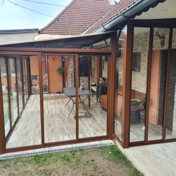 Zasklenie terasy vo farbe RAL 8003 s výhľadom do záhrady, bledohnedé jednosklo.