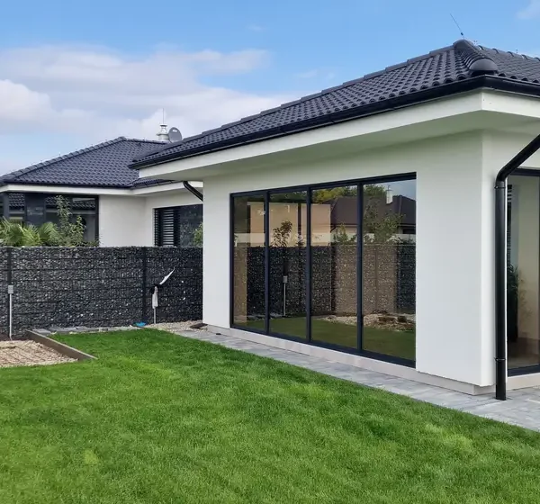 Bočný pohľad na zasklenú terasu rodinného domu v obci Veľký Lég v antracitovej farbe.