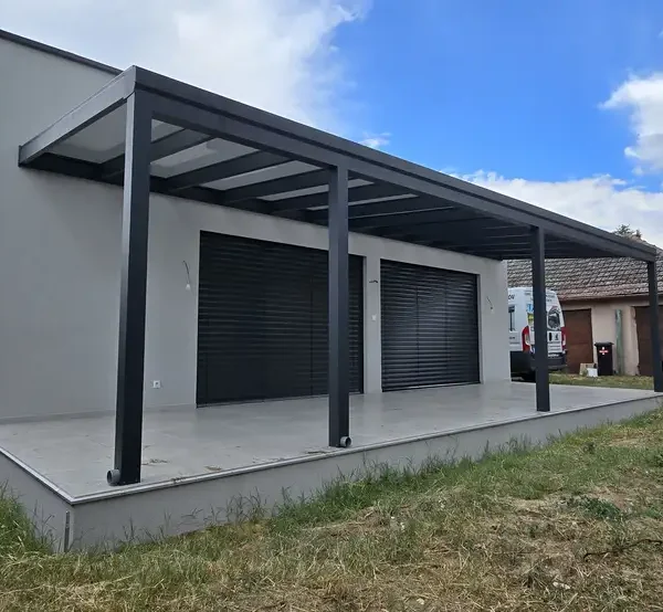 Bočný pohľad na hliníkovú pergolu s rozmermi 10 x 3,2 m v Šajdíkových Humenciach, ktorá poskytuje tienistý priestor pre vonkajšie aktivity.