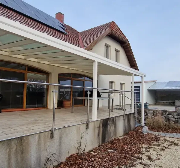 Exteriér rodinného domu v Hagenbrunne s hliníkovou pergolou 11x4 m na vyvýšenej terase, biela farba RAL 9003.