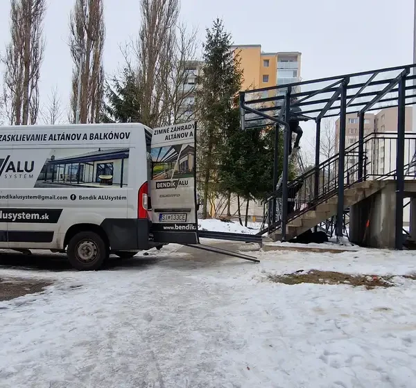 Montáž oceľového prístrešku s bezpečnostným sklom pred vchodom do bytovky v Považskej Bystrici, antracitová farba RAL 7016.