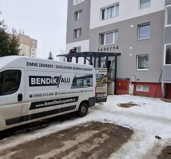 Oceľový prístrešok s bezpečnostným sklom a zábradlím pred vchodom do bytovky v Považskej Bystrici, realizácia v antracitovej farbe RAL 7016.