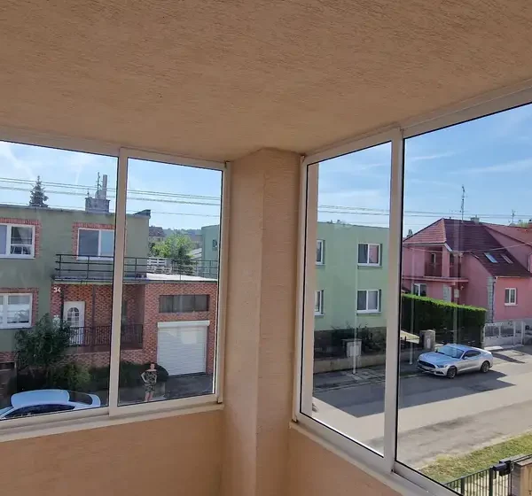 Zasklenie balkónu na rodinnom dome v Skalici, s čírymi sklenenými panelmi v bielom hliníkovom ráme (RAL 9003), poskytuje nerušený výhľad na okolitú štvrť.