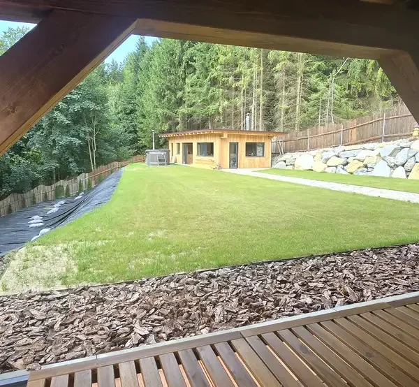 Pohľad z terasy na záhradu zasklenej drevenej terasy na chalupe v Turzovke, realizovaná s rámovým systémom v antracitovej farbe RAL 7016.