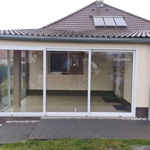 Predný pohľad na zasklenú terasu v Gbeloch, kde je vidieť elegantné biele rámy hliníkového systému Cortizo 2000.
