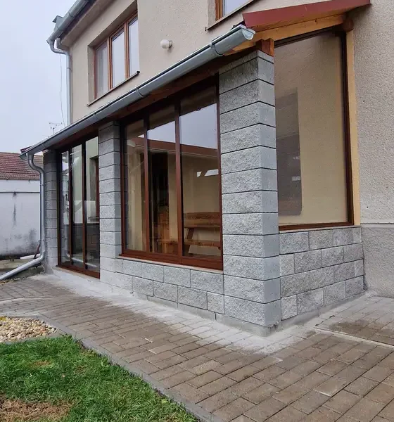 Bočný pohľad na zasklenie terasy posuvným hliníkovým systémom a atypickým fixným oknom v tmavohnedej farbe RAL 8017 v obci Kúty.