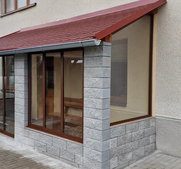 Zasklenie terasy posuvným hliníkovým systémom v tmavohnedej farbe RAL 8017 v obci Kúty, detail exteriéru ukazujúci pevné sklenené prvky.
