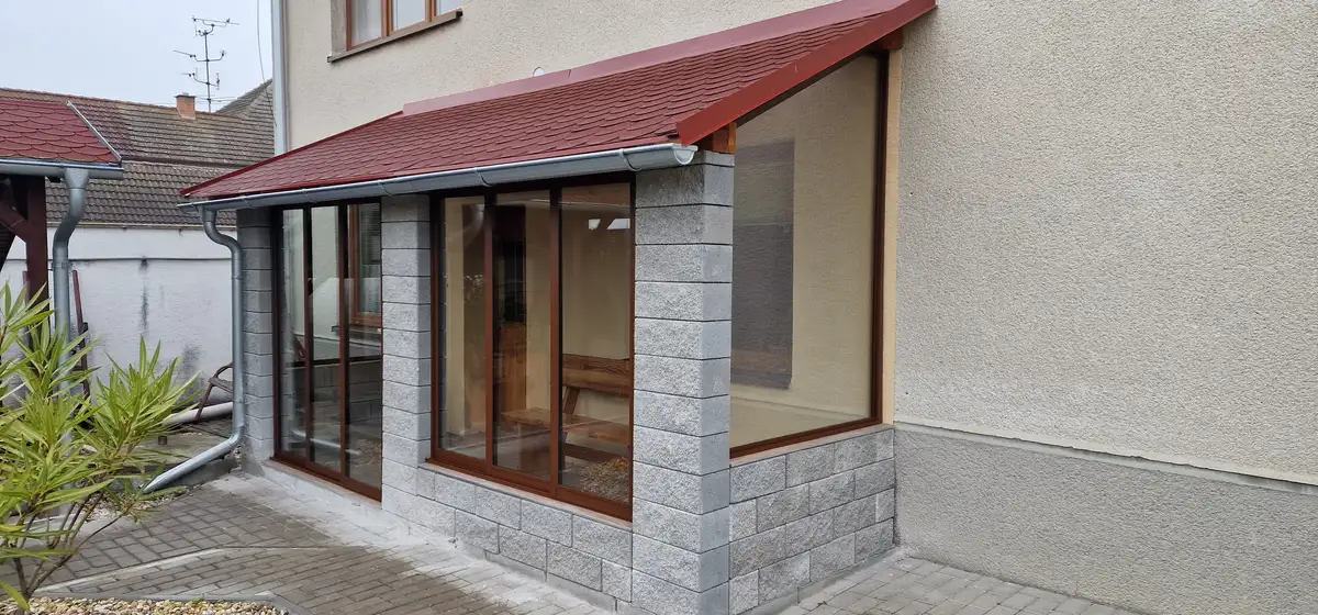 Zasklenie terasy posuvným hliníkovým systémom v tmavohnedej farbe RAL 8017 v obci Kúty, detail exteriéru ukazujúci pevné sklenené prvky.