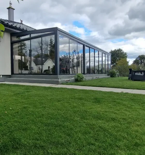 Bočný pohľad na zimnú záhradu 10x4 m s posuvným hliníkovým systémom a izolačným dvojsklom v antracitovej farbe RAL 7016, umiestnená na záhrade rodinného domu v Ležiachove.